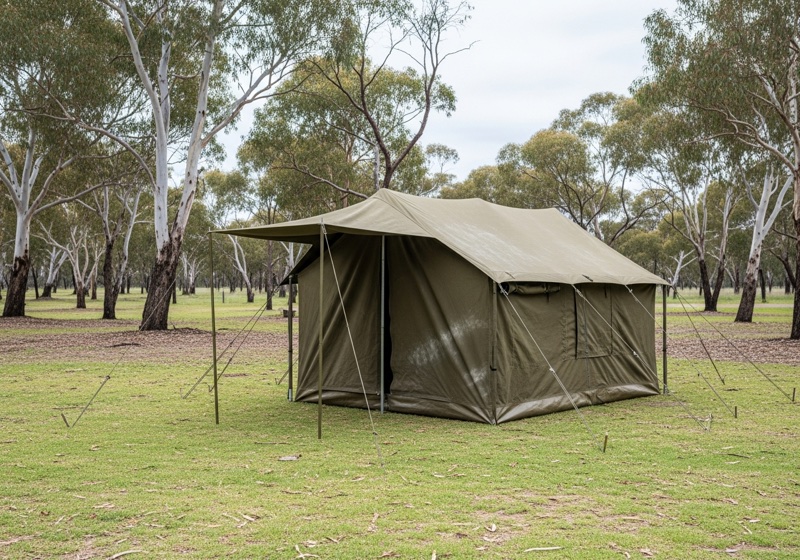 Canvas touring tent set up in a grassy paddock with gum trees