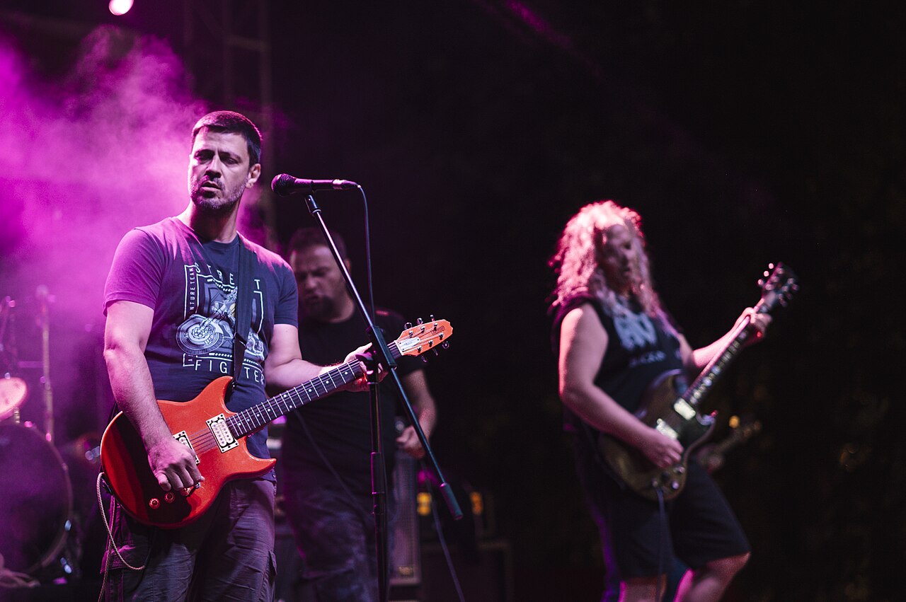 A band playing on stage under coloured lights at night