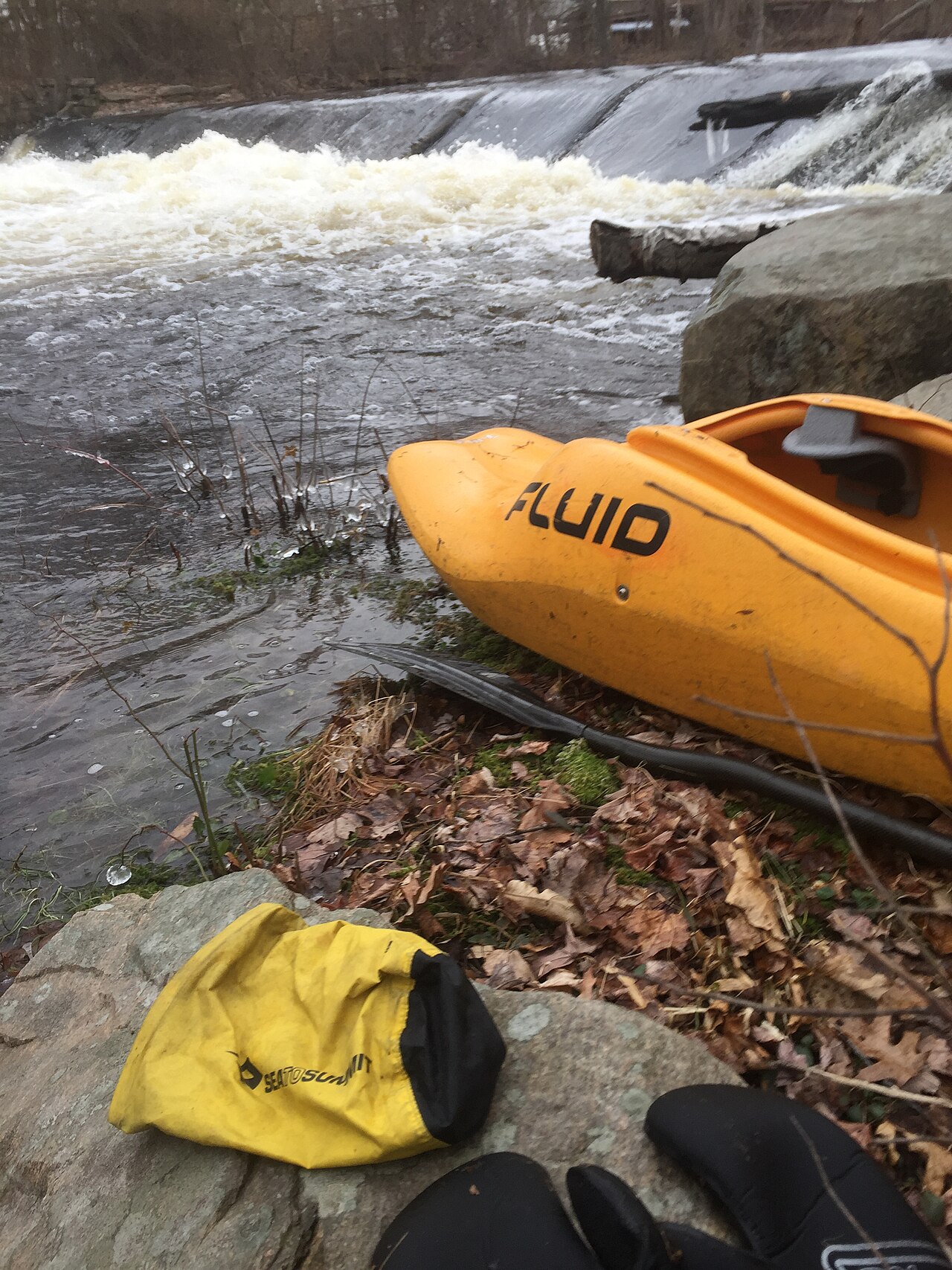 A kayak resting beside a flowing river