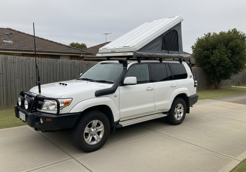 Hardshell rooftop tent mounted on a four-wheel-drive in a driveway